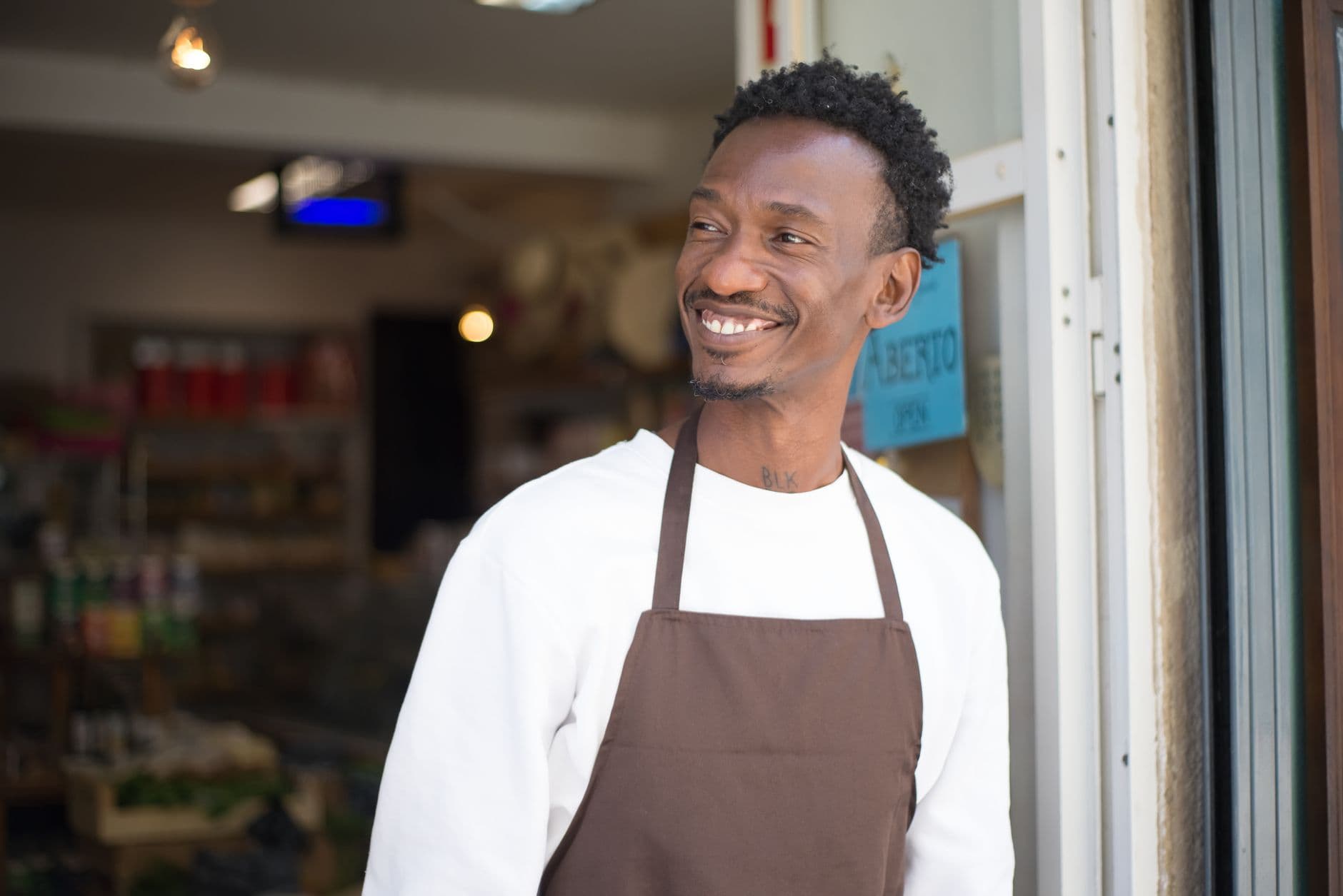 A smiling shop owner welcoming customers at the entrance of their store